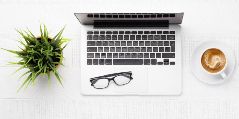Minimal home office workspace with laptop, glasses, coffee, and plant on a desk, representing a secure remote work environment