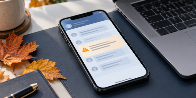 Smartphone displaying an illustrated message alert beside a laptop and orange autumn leaves.